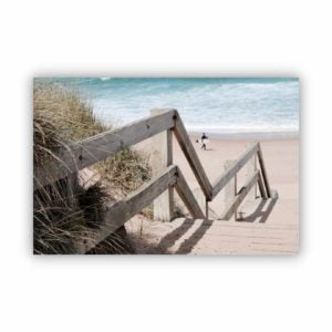 wall art canvas print of wooden beach stairs with a view of a surfer by the beach below.