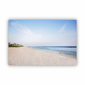 Photograph of a beautiful beach sand, blue ocean and blue sky.